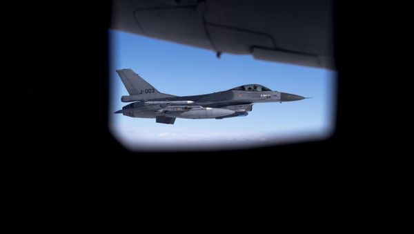 Seen through the window of another aircraft, an Royal Netherlands Air Force F- 16 military fighter jet participating in NATO's Baltic Air Policing Mission operates in Lithuanian airspace during a Ramstein Alloy air force exercise, Tuesday, April 25, 2017 - Sputnik International
