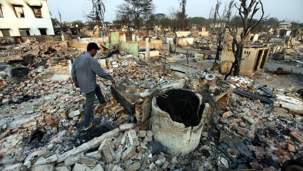 A man walks among debris of buildings destroyed during ethnic unrest between Buddhists and Muslim in Meikhtila, about 550 kilometers (340 miles) north of Yangon, Myanmar, Monday, March 25, 2013 - Sputnik International