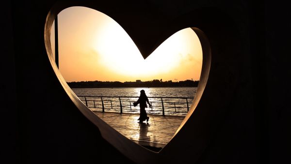 Saudi woman seen through a heart-shaped statue walks along an inlet of the Red Sea in Jiddah, Saudi Arabia - Sputnik International