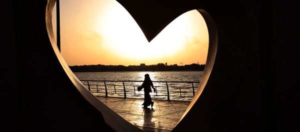 Saudi woman seen through a heart-shaped statue walks along an inlet of the Red Sea in Jiddah, Saudi Arabia - Sputnik International