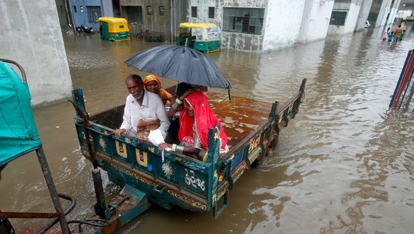 People sit in a tractor trolley as they move out of a flooded neighbourhood after heavy rain in Ahmedabad, India, July 24, 2017.  - Sputnik International