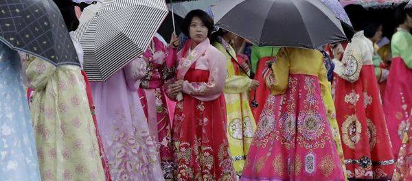 University students wearing traditional Korean dresses wait in the rain for the start of a mass dance on Thursday, July 27, 2017, in Pyongyang, North Korea as part of celebrations for the 64th anniversary of the armistice that ended the Korean War. - Sputnik International
