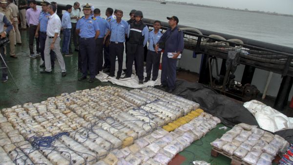 In this Sunday, July 30, 2017 photo, Indian coast guard officials, in blue, stand next to a massive amount of heroin they claim to have seized from a ship off the country's western coast near Porbandar, India - Sputnik International