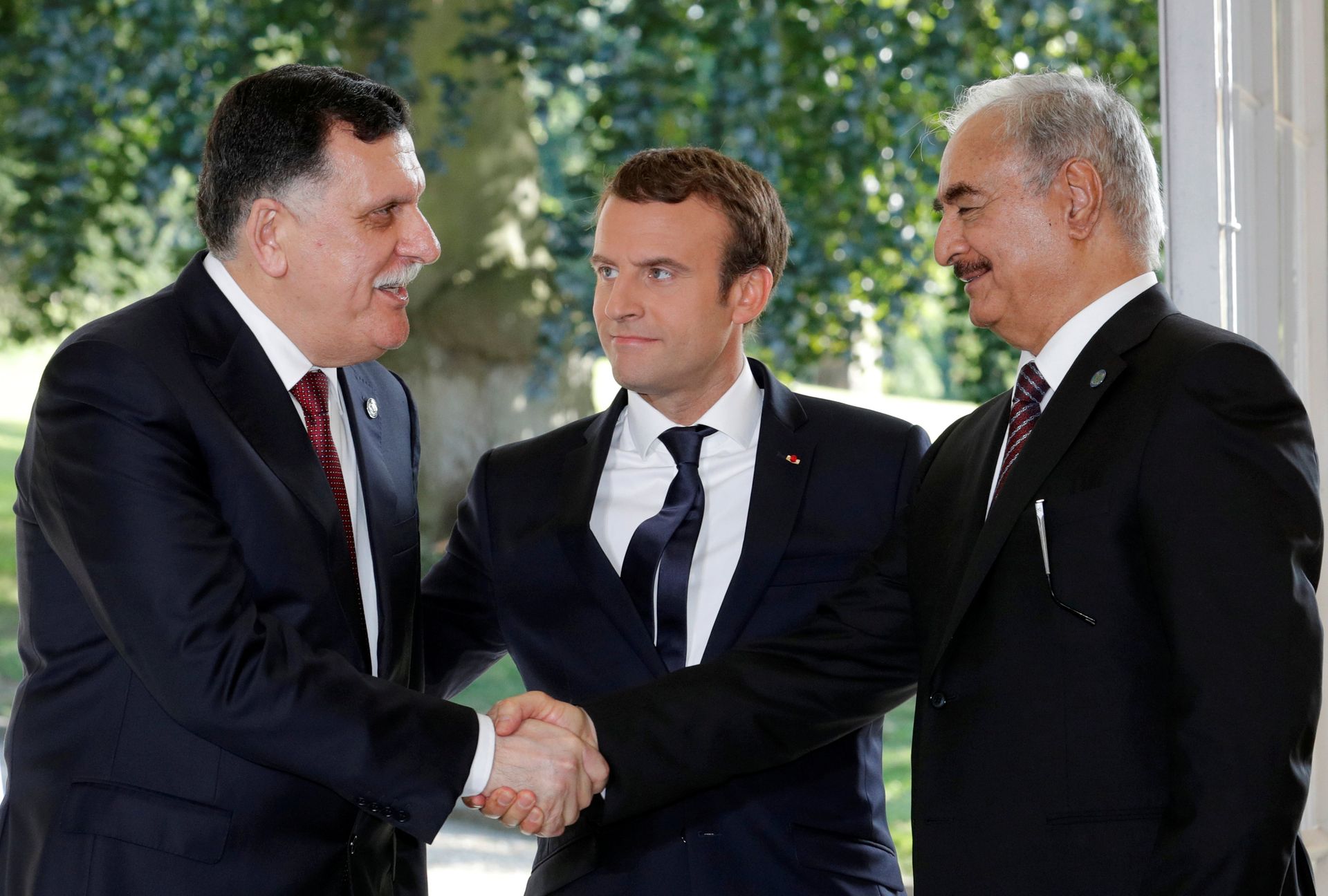 French President Emmanuel Macron stands between Libyan Prime Minister Fayez al-Sarraj (L), and General Khalifa Haftar (R), commander in the Libyan National Army (LNA), who shake hands after talks over a political deal to help end Libya’s crisis in La Celle-Saint-Cloud near Paris, France, July 25, 2017 French President Emmanuel Macron stands between Libyan Prime Minister Fayez al-Sarraj (L), and General Khalifa Haftar (R), commander in the Libyan National Army (LNA), who shake hands after talks over a political deal to help end Libya’s crisis in La Celle-Saint-Cloud near Paris, France, July 25, 2017 - Sputnik International, 1920, 21.12.2021