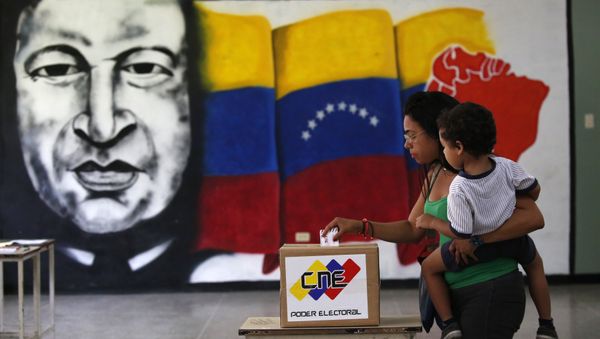 A woman holds her infant as she casts her vote in front of a mural of the late Venezuelan President Hugo Chavez at a polling station during the Constituent Assembly election in Caracas, Venezuela, July 30, 2017. A woman holds her infant as she casts her vote in front of a mural of the late Venezuelan President Hugo Chavez at a polling station during the Constituent Assembly election in Caracas, Venezuela, July 30, 2017. - Sputnik International