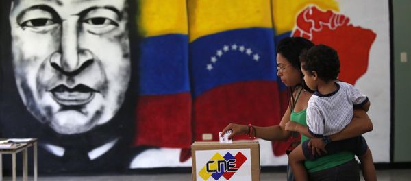A  woman holds her infant as she casts her vote in front of a mural of the late Venezuelan President Hugo Chavez at a polling station during the Constituent Assembly election in Caracas, Venezuela, July 30, 2017. - Sputnik International
