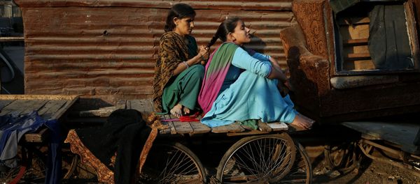A woman ties the hair of her daughter into a braid as they sit on a cart before evening sets in at a poor neighborhood in New Delhi, India, Thursday, Dec. 5, 2013 - Sputnik International