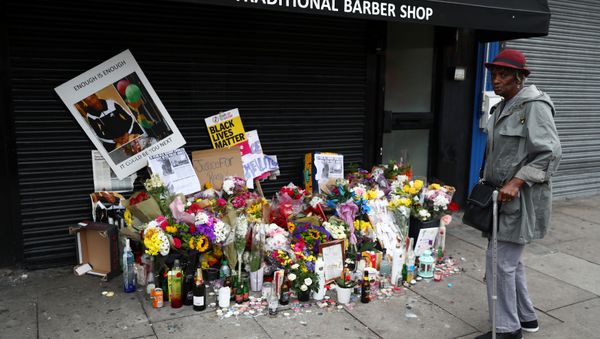 A woman looks at floral tributes laid after the death of Rashan Charles outside a shop in east London - Sputnik International
