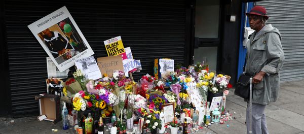 A woman looks at floral tributes laid after the death of Rashan Charles outside a shop in east London - Sputnik International