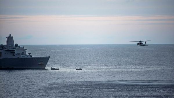 In this Saturday, Aug. 5, 2017, sailors man small boats as an MH-60S Sea Hawk helicopter, assigned to Helicopter Sea Combat Squadron (HSC) 25 flies overhead to recover personnel near the amphibious transport dock USS Green Bay (LPD 20) following an aviation mishap of an MV-22 Osprey, which caused the aircraft to enter the water off the coast of Australia. - Sputnik International