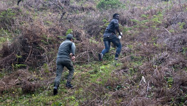 A member of the Moroccan authorities runs after a migrant on February 18, 2017 after he forced his way through a fence between Morocco and the tiny Spanish enclave of Ceuta - Sputnik International