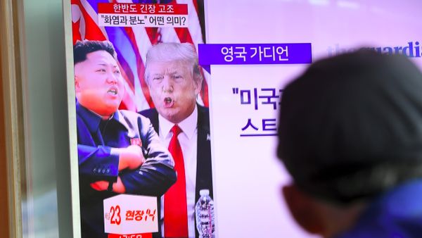 A man watches a television news programme showing US President Donald Trump (C) and North Korean leader Kim Jong-Un (L) at a railway station in Seoul on August 9, 2017 - Sputnik International