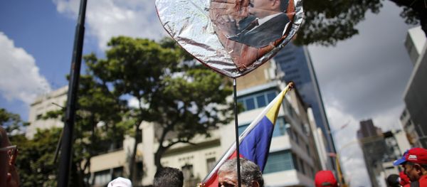 A government supporter holds a heart-shaped placard decorated with an image of Venezuela's Nicolas Maduro during a rally in support of the Constitutional Assembly outside of the National Assembly building in Caracas, Venezuela, Monday, Aug. 7, 2017. - Sputnik International