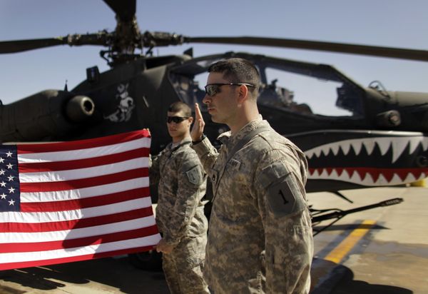 In this March 16, 2011, file photo Army Staff Sgt. Christopher Seeman, right, of Kalispell, Mont., takes the oath of re-enlistment as Spc. Brian Martinez, center, of Aurora, Ill., holds up a American flag in front of an Apache helicopter during a ceremony at Camp Taji, north of Baghdad, Iraq.  - Sputnik International
