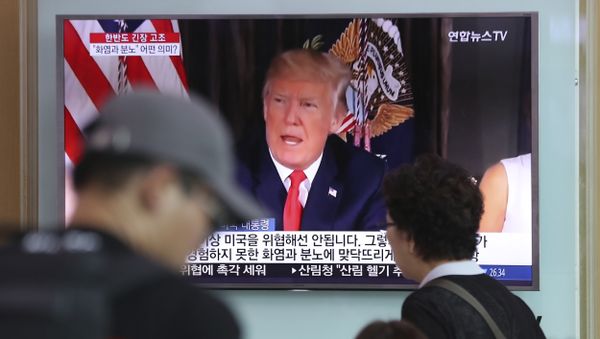 People walk by a TV screen showing a local news program reporting with an image of U.S. President Donald Trump at the Seoul Train Station in Seoul, South Korea, Wednesday, Aug. 9, 2017 - Sputnik International