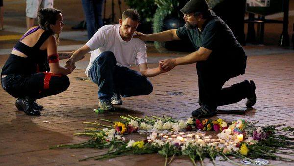 Two people stop to comfort a man as he kneels at a late night vigil to pay his respect for a friend injured in a car attack on counter protesters after a march organized by white nationalists in Charlottesville, Virginia, U.S., August 12, 2017 - Sputnik International