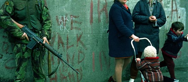 Women and children stand near an armed British military soldier patrols a street in Belfast, Northern Ireland, Feb. 1972. British paratroopers shot 13 demonstrators during a civil rights march on Jan. 30, known as Bloody Sunday. - Sputnik International