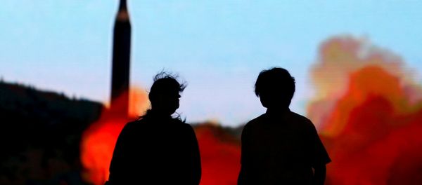 People walk in front of a monitor showing news of North Korea's fresh threat in Tokyo, Japan, August 10, 2017. - Sputnik International