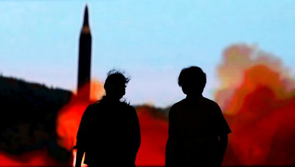 People walk in front of a monitor showing news of North Korea's fresh threat in Tokyo, Japan, August 10, 2017. - Sputnik International