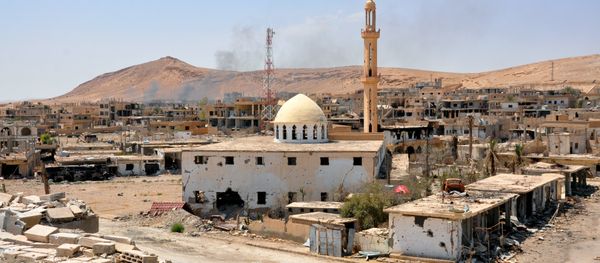 Smoke rising from buildings behind a mosque in the central Syrian town of Al-Sukhnah Smoke rising from buildings behind a mosque in the central Syrian town of Al-Sukhnah - Sputnik International