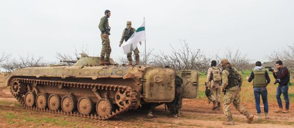A picture taken on March 22, 2017 near the town of Maardes in the countryside of the central Syrian province of Hama, shows rebel fighters walking past an armoured vehicle carrying the flag of the Tahrir al-Sham rebel alliance A picture taken on March 22, 2017 near the town of Maardes in the countryside of the central Syrian province of Hama, shows rebel fighters walking past an armoured vehicle carrying the flag of the Tahrir al-Sham rebel alliance - Sputnik International