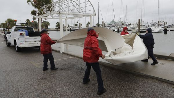 City workers pull down a canvas covering as the outer bands of Hurricane Harvey move closer, Friday, Aug. 25, 2017, in Corpus Christi, Texas - Sputnik International