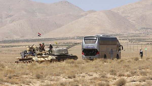 Syrian forces members stand on a tank next to a vehicle waiting to transport Islamic State (IS) group members in the Qara area in Syria's Qalamoun region on August 28, 2017 as part of a deal between Hezbollah and IS fighters where the jihadists would leave to eastern Syria - Sputnik International
