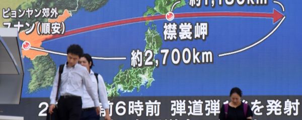Pedestrians walk in front of a huge screen displaying a map of Japan (R) and the Korean Peninsula, in Tokyo on August 29, 2017, following a North Korean missile test that passed over Japan. - Sputnik International