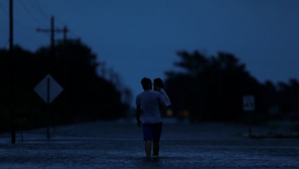 Ethan holds his 2-year-old daughter Zella as they walk through flood waters from Tropical Storm Harvey in Iowa, Calcasieu Parish, Louisiana, U.S - Sputnik International