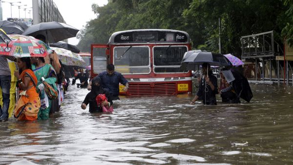 People walk through a waterlogged street following heavy rains in Mumbai, India People walk through a waterlogged street following heavy rains in Mumbai, India - Sputnik International