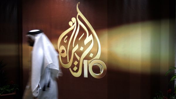 A Qatari employee of Al Jazeera Arabic language TV news channel passes by the logo of Al Jazeera in Doha, Qatar. (File) A Qatari employee of Al Jazeera Arabic language TV news channel passes by the logo of Al Jazeera in Doha, Qatar. (File) - Sputnik International