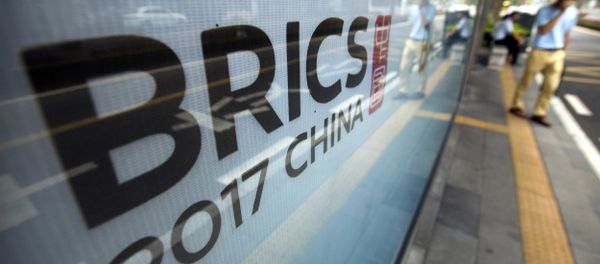 A man stands near a billboard advertising the 2017 BRICS Summit at a bus shelter in Xiamen in southeastern China's Fujian Province, Saturday, Sept. 2, 2017 - Sputnik International