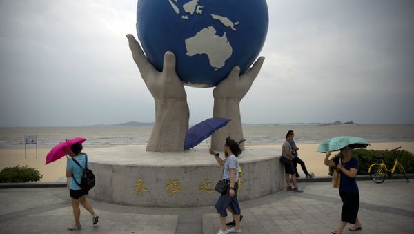 People carry umbrellas as they walk along a beach adjacent to the venue for the upcoming BRICS Summit in Xiamen in southeastern China's Fujian Province, Saturday, Sept. 2, 2017 - Sputnik International