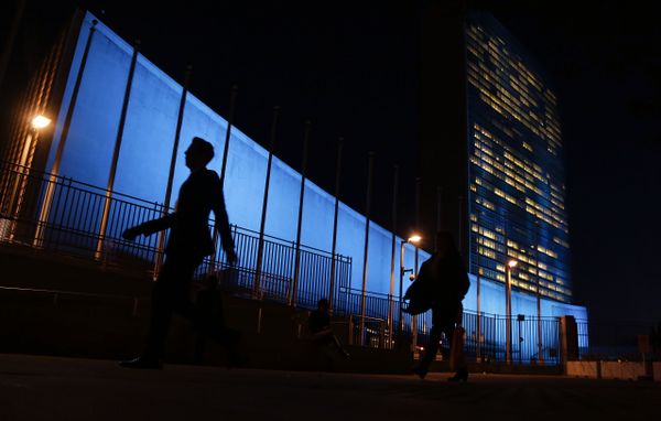 Pedestrians walk by United Nations Headquarters, lit up in blue light, a day in advance of the 70th Anniversary of the U.N., in New York City. File Photo. - Sputnik International