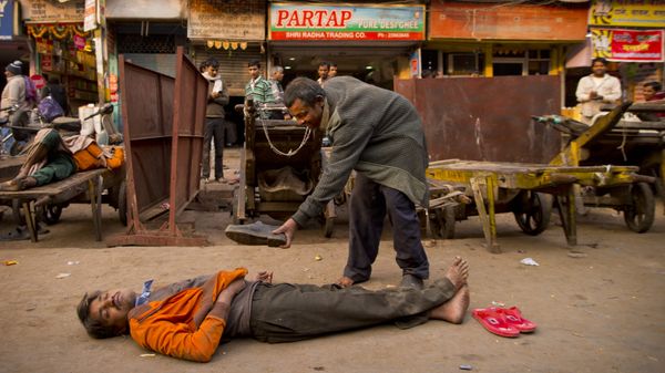 In this Friday, Dec. 12, 2014 photo, a drunk man offers his shoes to his colleague who passed out after consuming alcohol in New Delhi, India - Sputnik International