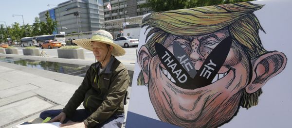 A South Korean protester sits next to a poster with an illustration of U.S. President Donald Trump to oppose a plan to deploy an advanced U.S. missile defense system called Terminal High-Altitude Area Defense, or THAAD, near the U.S. Embassy in Seoul Monday, June 5, 2017 - Sputnik International