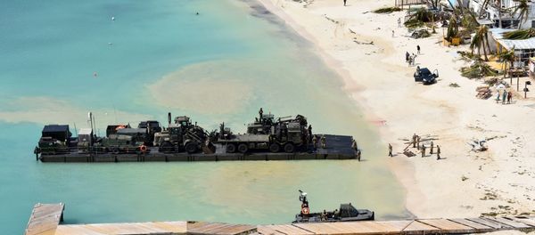In this undated photo provided by the Ministry of Defence on Friday, Sept. 8, 2017, taken from a Royal Navy helicopter, a RLC Mexeflote approaches Sandy Bay Village beach, in Anguilla loaded with the 2 JCBs, 1 flatbed lorry, fork lift truck, BV 206 multi terrain vehicle, a Land Rover and a mobile generator. - Sputnik International