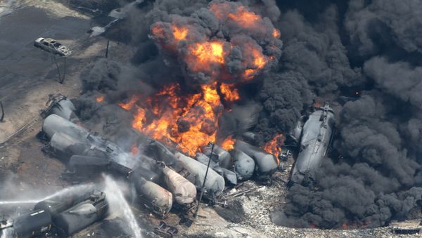 Smoke rises from railway cars that were carrying crude oil after derailing in downtown Lac Megantic, Quebec, Saturday, July 6, 2013. - Sputnik International