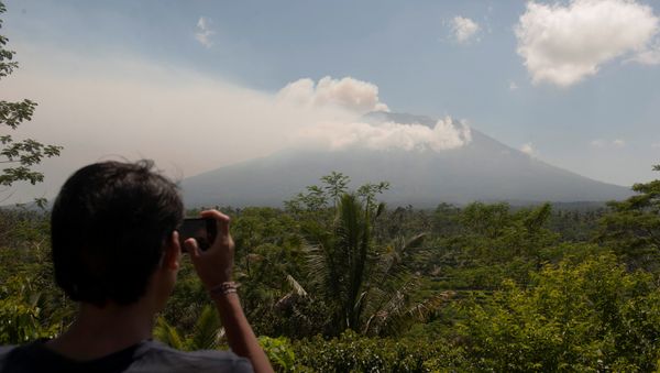 A local resident takes a picture of Mount Agung, an active volcano that authorities say is showing increased activity, from a monitoring station in Rendang Village, Karangasem on the resort island of Bali, Indonesia September 19, 2017 - Sputnik International