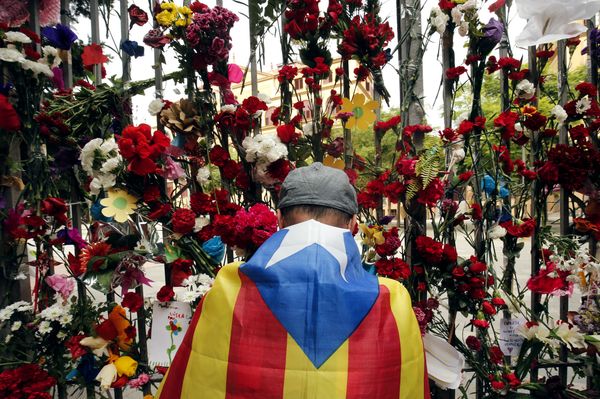 A man wrapped in a Catalan pro-independence 'Estelada' flag puts flowers on the gate of Barcelona's Ramon Llull School, which was used as a polling station and was one of those targeted by riot police during the October 1 banned independence referendum, as Catalonia observes a general strike called by Catalan unions on October 3, 2017 A man wrapped in a Catalan pro-independence 'Estelada' flag puts flowers on the gate of Barcelona's Ramon Llull School, which was used as a polling station and was one of those targeted by riot police during the October 1 banned independence referendum, as Catalonia observes a general strike called by Catalan unions on October 3, 2017 - Sputnik International