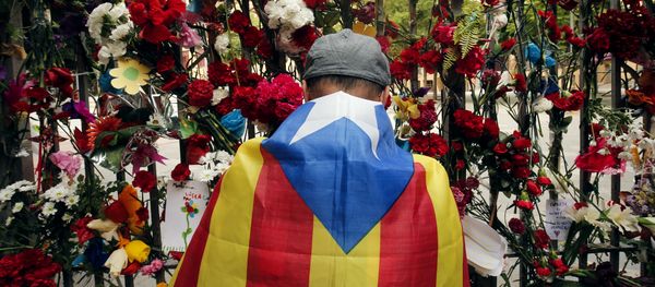 A man wrapped in a Catalan pro-independence 'Estelada' flag puts flowers on the gate of Barcelona's Ramon Llull School, which was used as a polling station and was one of those targeted by riot police during the October 1 banned independence referendum, as Catalonia observes a general strike called by Catalan unions on October 3, 2017 A man wrapped in a Catalan pro-independence 'Estelada' flag puts flowers on the gate of Barcelona's Ramon Llull School, which was used as a polling station and was one of those targeted by riot police during the October 1 banned independence referendum, as Catalonia observes a general strike called by Catalan unions on October 3, 2017 - Sputnik International