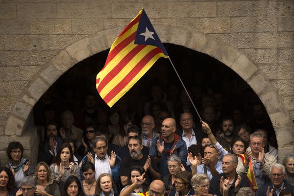 Catalan independence supporters, one waving an estelada, or Catalonia independence flag, applaud during a rally outside the city hall of Girona, Spain - Sputnik International