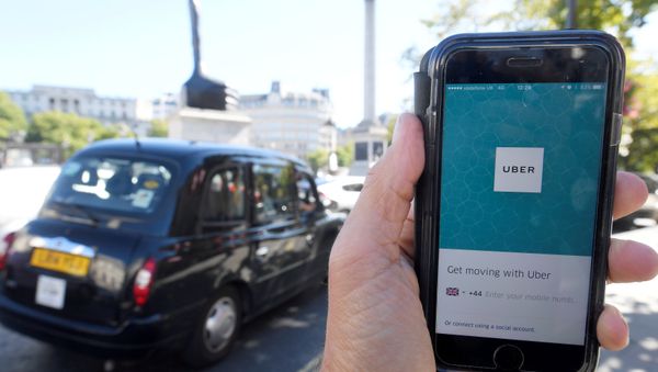 London taxi passing as the Uber app logo is displayed on a mobile telephone, as it is held up for a posed photograph in central London, Britain. (File) London taxi passing as the Uber app logo is displayed on a mobile telephone, as it is held up for a posed photograph in central London, Britain. (File) - Sputnik International