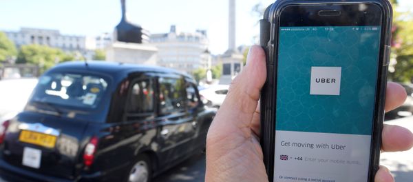 London taxi passing as the Uber app logo is displayed on a mobile telephone, as it is held up for a posed photograph in central London, Britain. (File) - Sputnik International