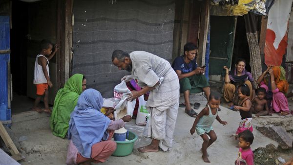 In this Tuesday, Sept. 12, 2017 photo, a Rohingya refugee distributes wheat, donated by locals, among other refugees at a camp for the refugees in New Delhi, India - Sputnik International