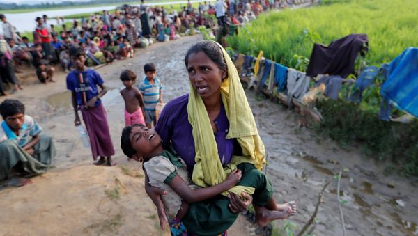A Rohingya refugee woman who crossed the border from Myanmar a day before, carries her daughter and searches for help as they wait to receive permission from the Bangladeshi army to continue their way to the refugee camps, in Palang Khali, Bangladesh October 17, 2017 A Rohingya refugee woman who crossed the border from Myanmar a day before, carries her daughter and searches for help as they wait to receive permission from the Bangladeshi army to continue their way to the refugee camps, in Palang Khali, Bangladesh October 17, 2017 - Sputnik International