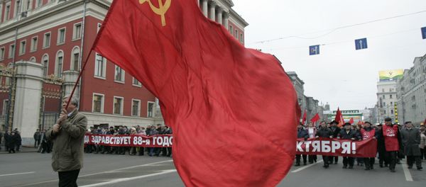 Communist supporter carries the red flag as others carry a banner declaring Long Live the 88th Anniversary of the October Revolution, during the rally to commemorate the Bolshevik Revolution, marking a long-sacred former holiday that was an official working day for the first time in decades in Moscow, Monday, Nov. 7, 2005. - Sputnik International