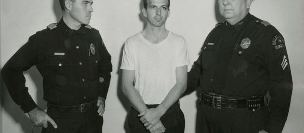 Lee Harvey Oswald, accused of assassinating former U.S. President John F. Kennedy, is pictured with Dallas police Sgt. Warren (R) and a fellow officer in Dallas, in this handout image taken on November 22, 1963. - Sputnik International