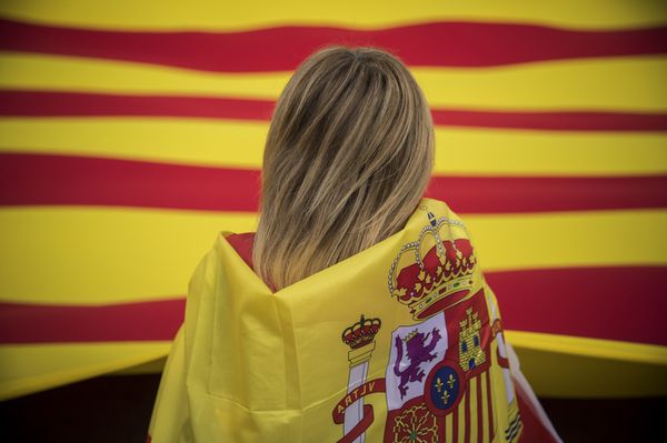 A woman wearing a Spanish flag on her shoulders looks at a giant flag of Catalonia as people celebrate a holiday known as Dia de la Hispanidad or Spain's National Day in Barcelona, Spain, Thursday, Oct. 12, 2017.  - Sputnik International