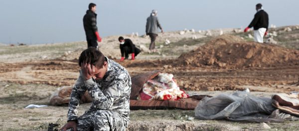 An Iraqi policeman collects himself at the burial site for bodies found in a mass grave containing some two dozen people, many of them children, in an area recently re-taken from Islamic State militants in Hamam al-Alil, Iraq, Wednesday, March 15, 2017 - Sputnik International